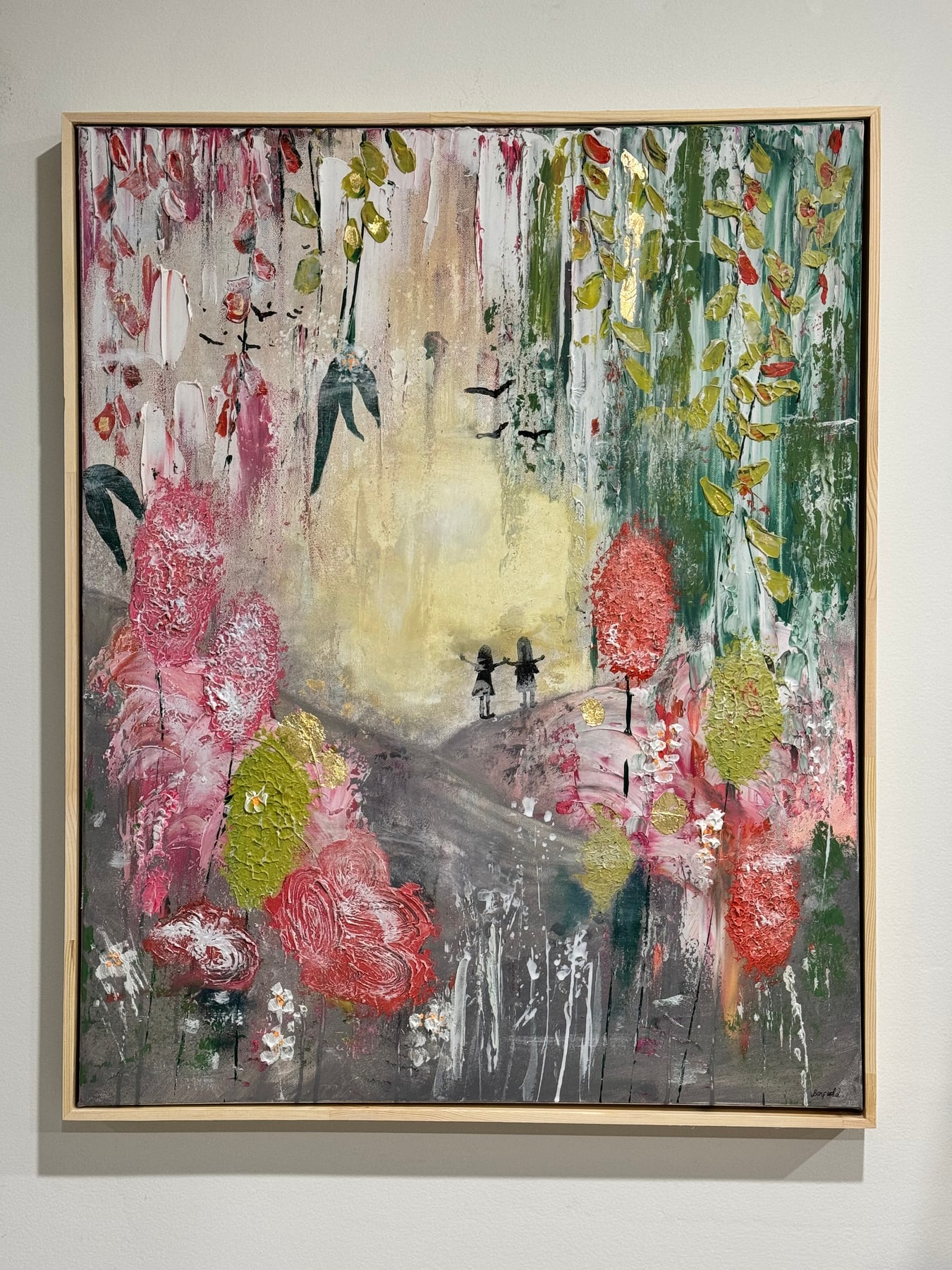 Framed landscape painting: two tiny figures on a hill among pink and gold trees under a pale washed sky.