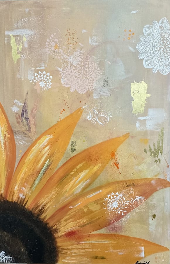 A large golden sunflower head at the lower left of a warm, softly patterned ground.