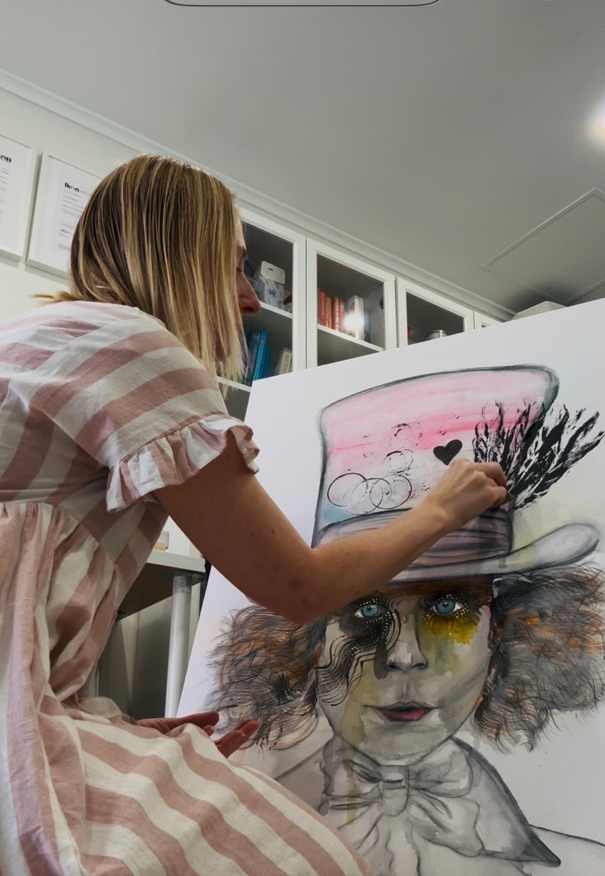 Niki working on a large drawing of a figure in a top hat, in her studio.